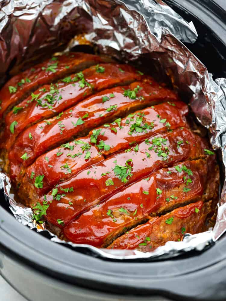 Meatloaf is a classic comfort food that is loved by the whole family! This recipe for crockpot meatloaf is easy to prepare, and using your slow cooker allows the flavors to blend together for a delicious meal. Meatloaf in a crockpot, cut into slices.