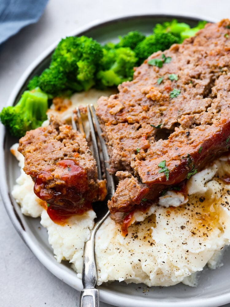 Meatloaf is a classic comfort food that is loved by the whole family! This recipe for crockpot meatloaf is easy to prepare, and using your slow cooker allows the flavors to blend together for a delicious meal. A slice of crockpot meatloaf served with broccoli and mashed potatoes.