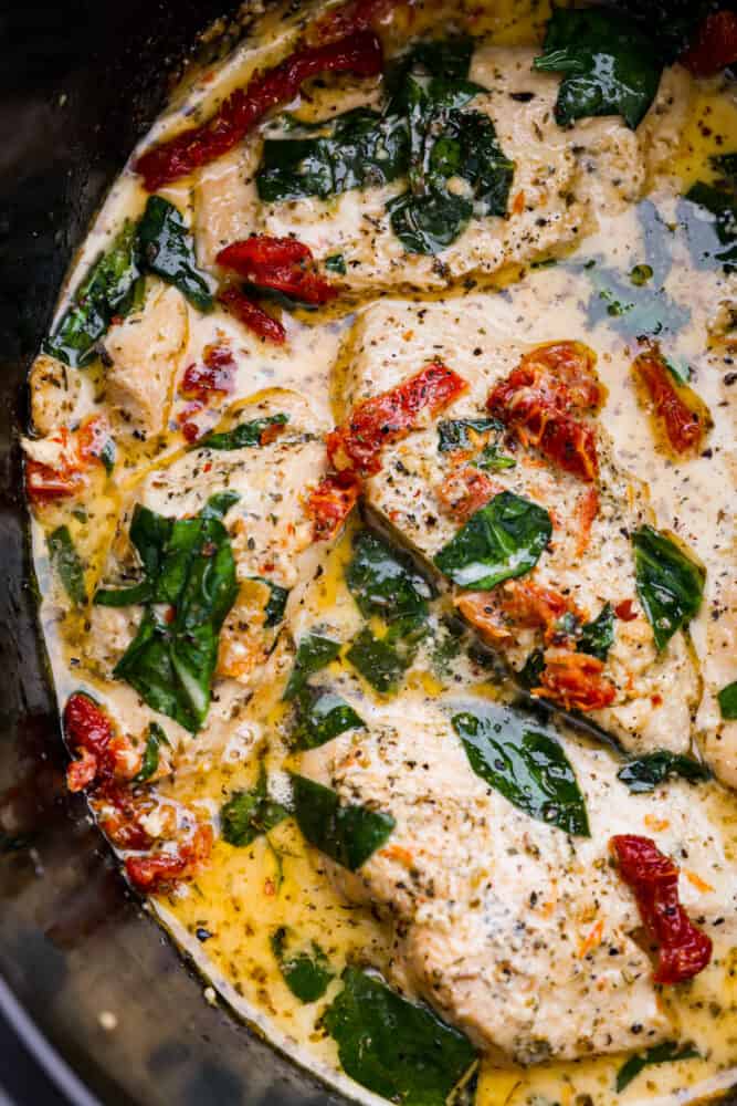 Crockpot Tuscan Chicken is delicious juicy and tender chicken breast cooked in a creamy parmesan and sun dried tomato sauce. It takes 10 minutes to prep and the smells alone will have your family asking when dinner is! A close up on the finished slow cooker chicken.