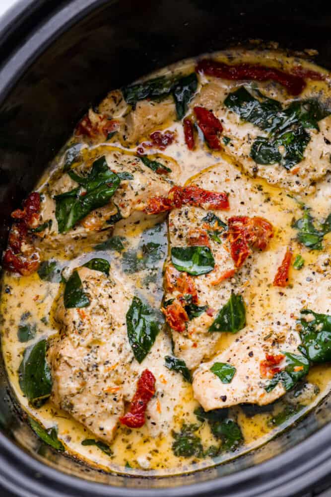 Crockpot Tuscan Chicken is delicious juicy and tender chicken breast cooked in a creamy parmesan and sun dried tomato sauce. It takes 10 minutes to prep and the smells alone will have your family asking when dinner is! Crockpot Tuscan chicken in a slow cooker.