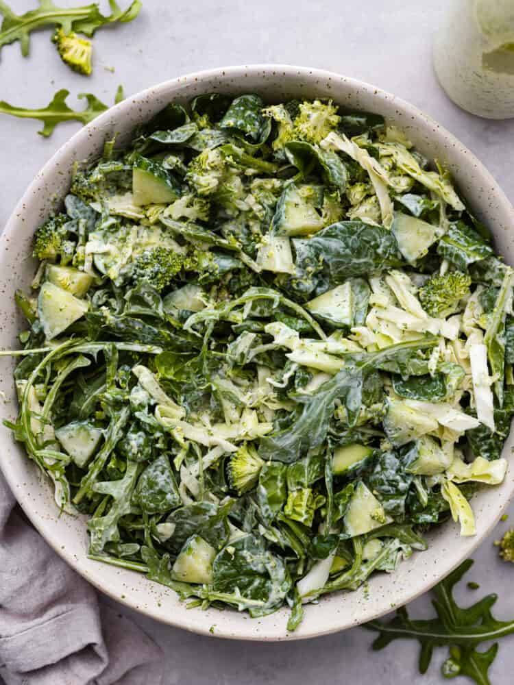 Meet your new favorite veggie fix- Green Goddess salad! Itโs packed with fresh lettuce, arugula, and spinach, tossed with green onions and the most flavorful Green Goddess dressing; creamy, savory goodness made with Greek yogurt, fresh herbs, and lemon! Top-down view of Green Goddess salad in a speckled bowl.