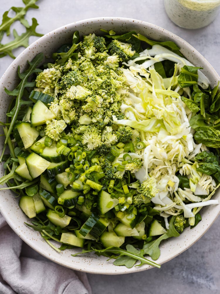 Meet your new favorite veggie fix- Green Goddess salad! Itโs packed with fresh lettuce, arugula, and spinach, tossed with green onions and the most flavorful Green Goddess dressing; creamy, savory goodness made with Greek yogurt, fresh herbs, and lemon! Top-down view of fresh vegetables.