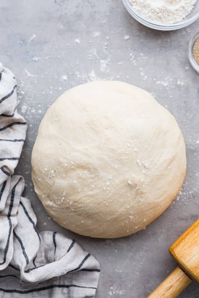 Pillowy soft, with the perfect taste and texture, this quick and easy pizza dough is going to be your go-to recipe for everything! You are going to want to keep this in the archives and use it over and over again. Pizza dough rolled into a ball.