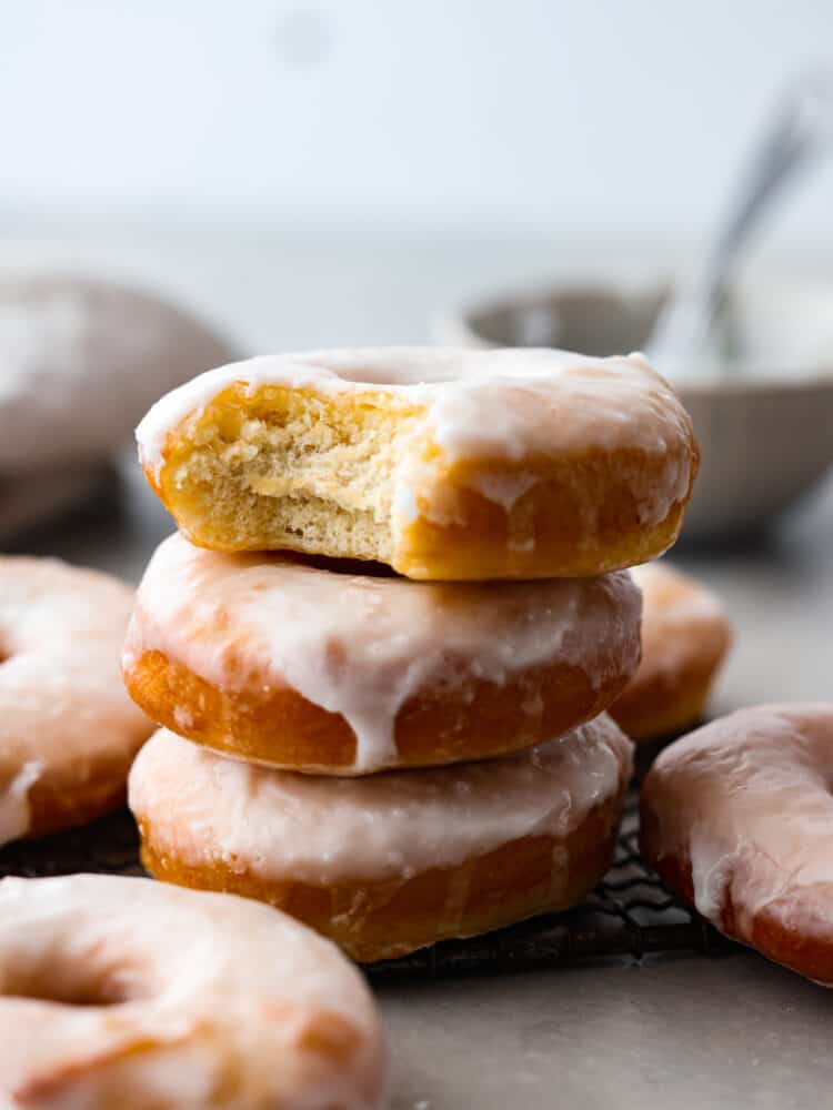 Homemade glazed donuts are light and fluffy with a perfectly moist inside and a sweetened glazed outside. They are the ultimate treat and super easy to make at home, which makes them the perfect dessert for any occasion. Seriously, who doesn't want a freshly fried homemade donut?! Fried glazed donuts stacked on top of each other with a bite taken out of the top one.