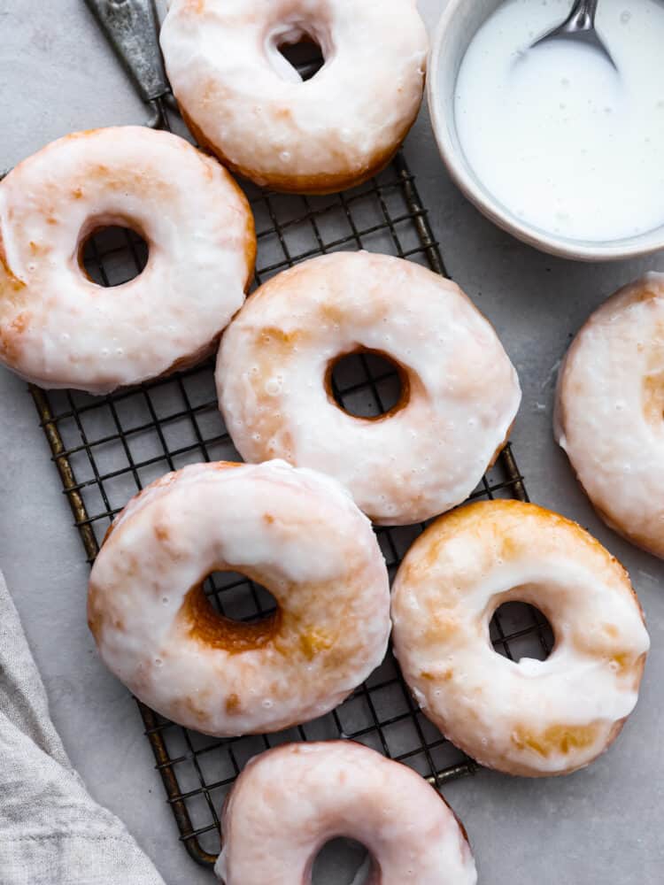 Homemade glazed donuts are light and fluffy with a perfectly moist inside and a sweetened glazed outside. They are the ultimate treat and super easy to make at home, which makes them the perfect dessert for any occasion. Seriously, who doesn't want a freshly fried homemade donut?! Delicious glazed donuts with glaze in a bowl.