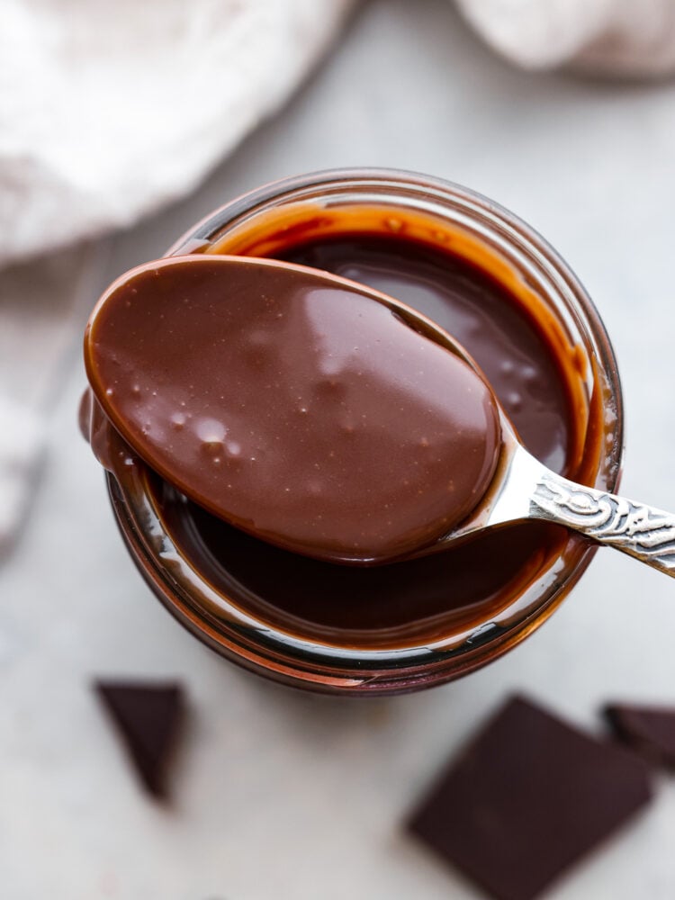 Homemade hot fudge is silky smooth and full of intense chocolate flavor without being too sweet. It is made up of 3 simple ingredients and ready in just 10 minutes. This is the perfect topping for hot fudge sundaes, fruit, and your favorite desserts! A spoon showing the hot fudge.