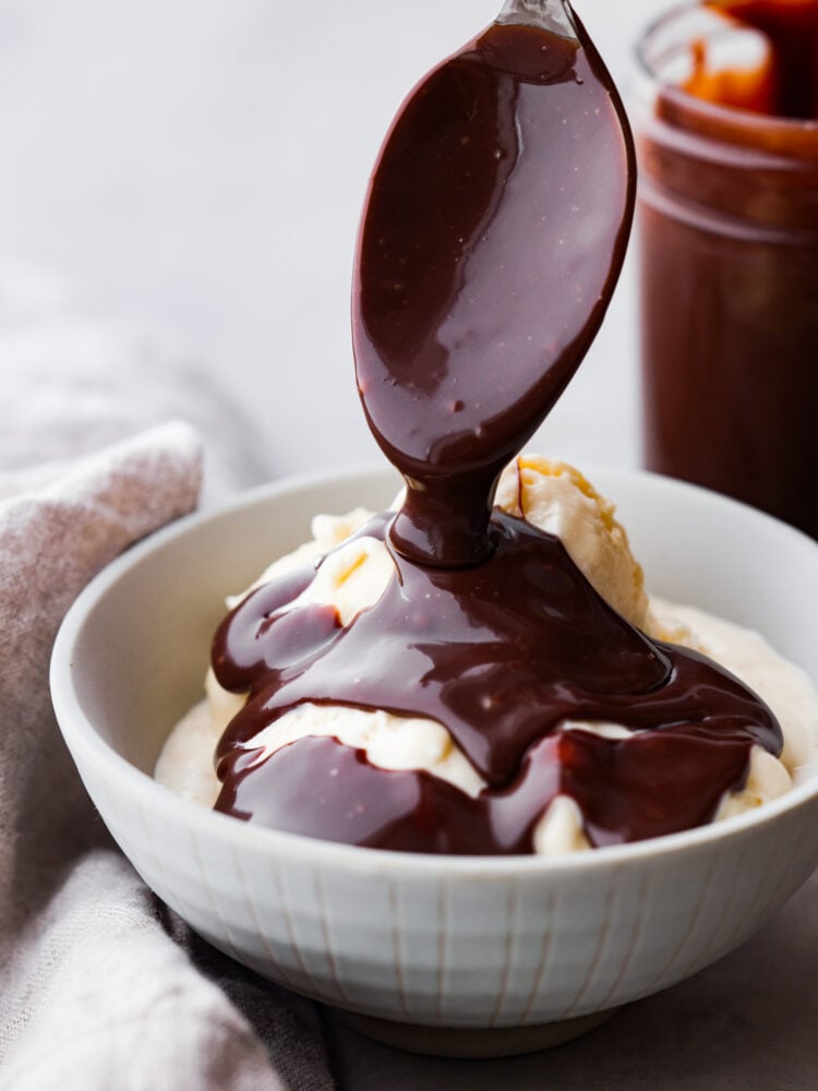 Homemade hot fudge is silky smooth and full of intense chocolate flavor without being too sweet. It is made up of 3 simple ingredients and ready in just 10 minutes. This is the perfect topping for hot fudge sundaes, fruit, and your favorite desserts! A spoon drizzling hot fudge over a bowl of ice cream.