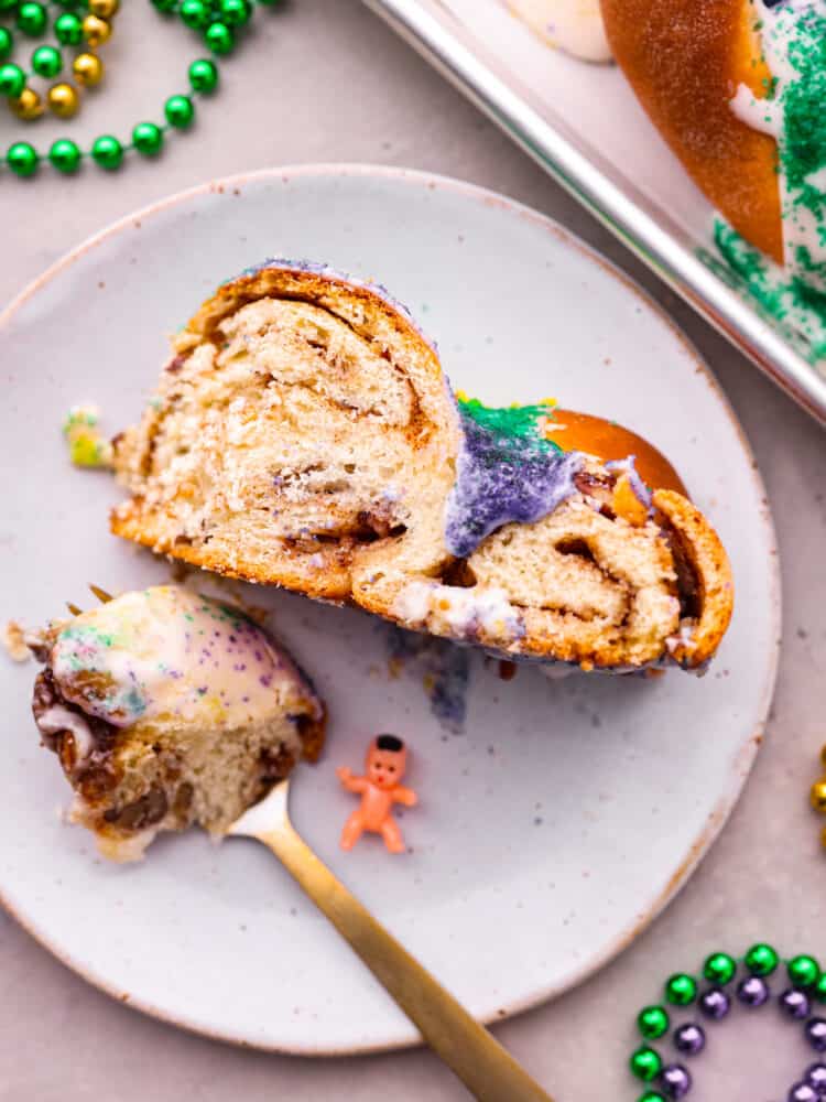 King cake is a colorful and festive dessert for Mardi Gras celebrations! With its gorgeous swirl of purple, green and gold icing, this sweet and soft cake is a treat for both the eyes and the taste buds. Whether you're a seasoned king cake aficionado or a newcomer to this sugary delight, there's no denying its irresistible charm! A slice of cake on a white plate.