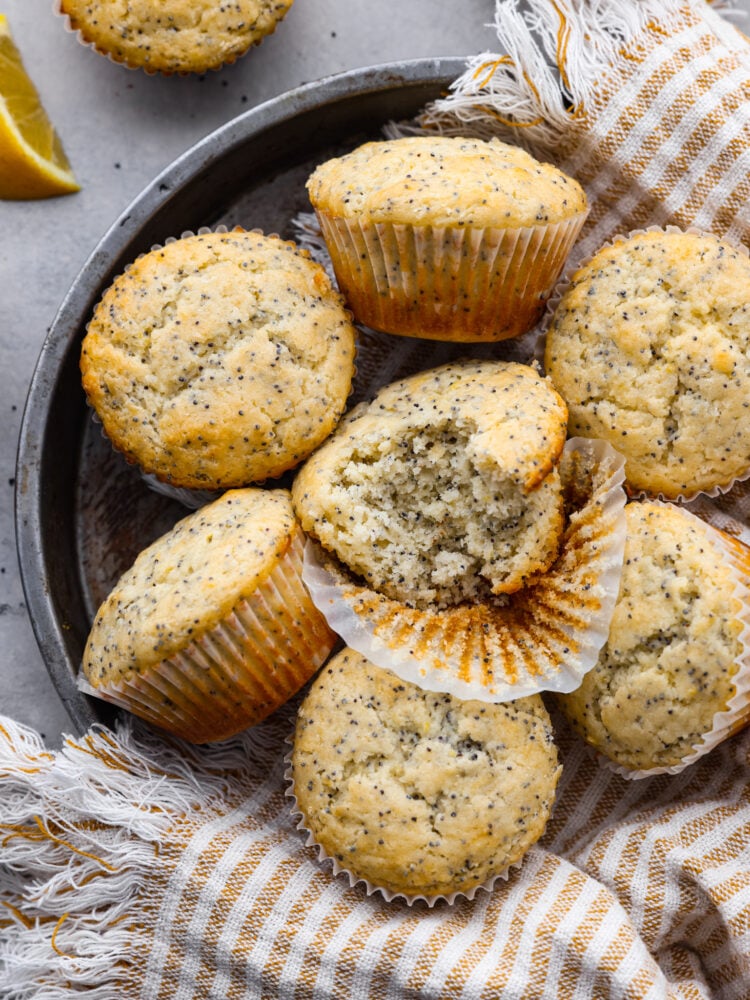 These lemon poppyseed muffins are super soft and loaded with fresh lemon flavor thanks to fresh juice and zest. Tender and moist, these muffins are the perfect breakfast or brunch companion! Top-down view of multiple lemon poppyseed muffins One has a bite taken out of it.