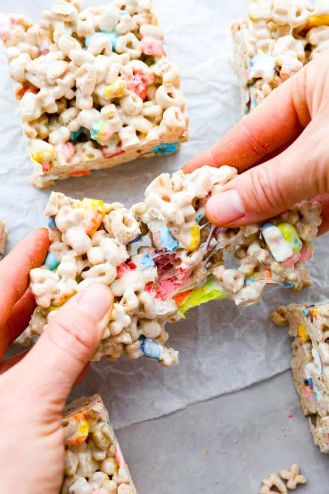 These Lucky Charms treats are a fun twist on the classic rice krispie treat and are every bit as magically delicious as you could imagine! They are sweet, but not too sweet to keep coming back for seconds and even thirds. They are a colorful and quick treat perfect for every occasion. A hand pulling apart the cereal bars.