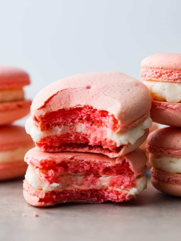This French macaron cookie recipe makes the perfect macaron every time! I share all of my tips and tricks to get the perfect feet on your macaron, and a delicate and airy cookie with a shiny smooth shell. You are going to love making these fun and elegant cookies at home! A close up of bites taken out of two macarons.