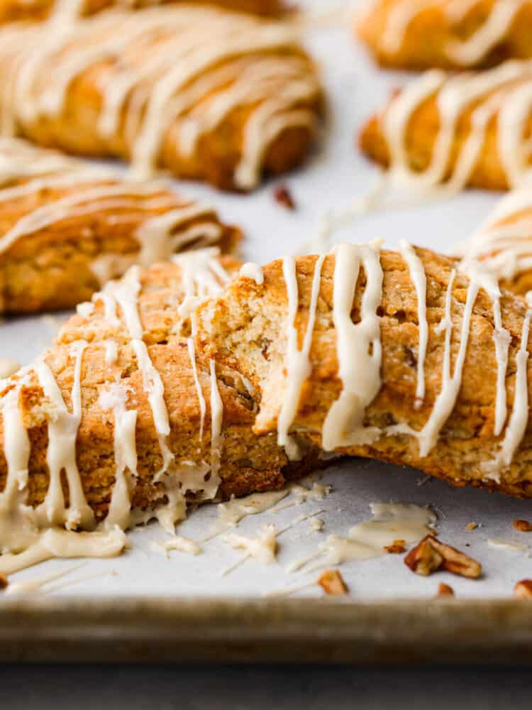 Golden and flaky Maple Pecan Scones are buttery soft and full of nutty flavor from toasted pecans and real maple syrup. They are melt in your mouth delicious and ridiculously easy to make! Maple pecan scones on a counter with a bite taken out of one.
