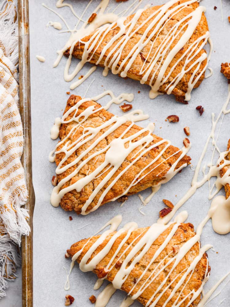 Golden and flaky Maple Pecan Scones are buttery soft and full of nutty flavor from toasted pecans and real maple syrup. They are melt in your mouth delicious and ridiculously easy to make! An overhead view of maple pecan scones with a maple drizzle.