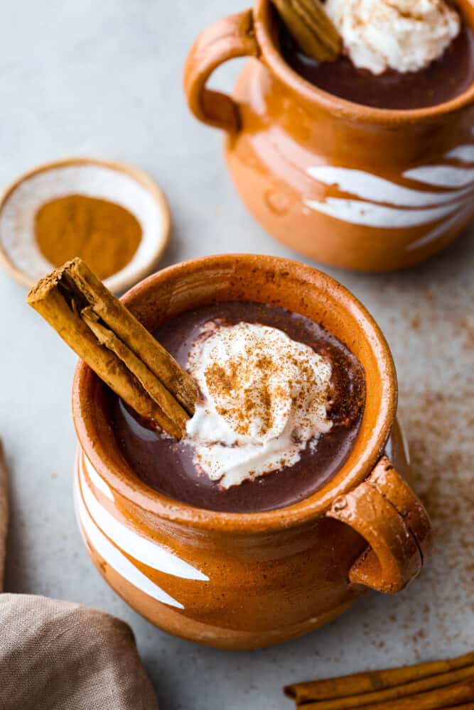 Spice up your hot cocoa game with a batch of this flavorful Mexican hot chocolate! It's rich and creamy with a touch of cinnamon and chili powder. The perfect remedy for chilly months! Mexican hot chocolate served in a tan colored mug, topped with a cinnamon stick.