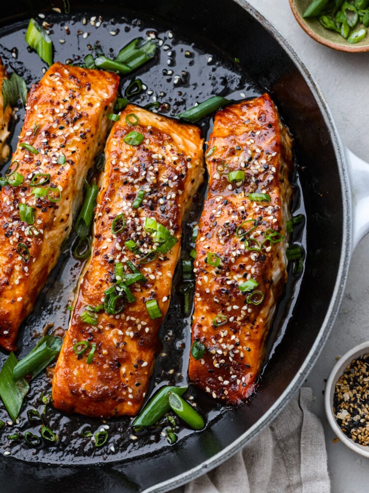 Better than at your favorite restaurant, this miso-glazed salmon is sweet, savory, and full of flavor. It cooks with a delicious caramelized miso glaze on the outside and stays flaky and moist in the middle. You are going to love everything about this recipe! Miso glazed salmon in a pan with sesame seeds and green onions on top.