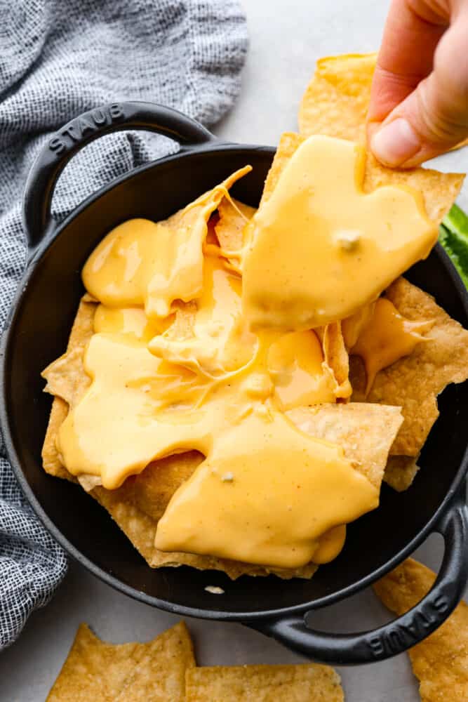 This Nacho Cheese recipe is the genuine Velveeta based topping that is full of nostalgia and amazing flavor! It's so simple to whip up and tastes way better than store-bought. Nacho cheese sauce in a skillet over tortilla chips.