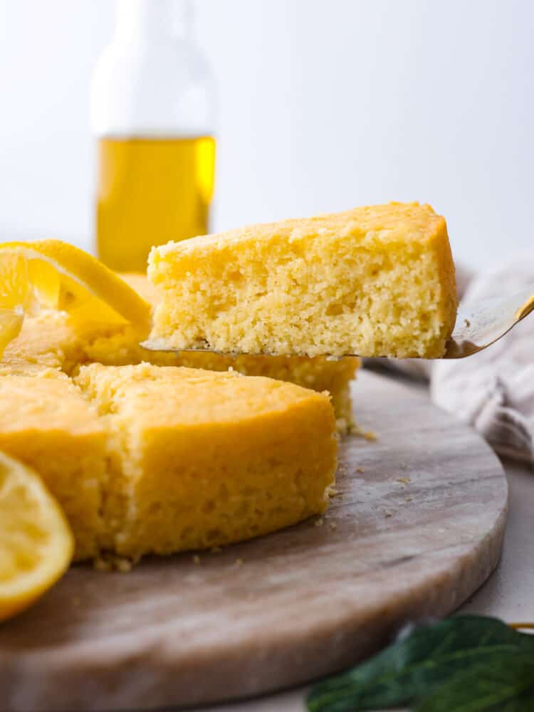 If youโve never tried it, (which you definitely should!) olive oil cake has a light and moist texture, with a slightly crispy crust. The flavor is delicate and subtle, with fruity and nutty notes. You will love every bite! A slice of olive oil cake being picked up with a cake spatula.