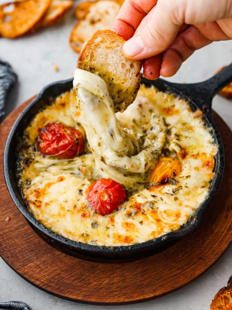 Provoleta is a traditional Argentine dish made from melted provolone cheese served in a hot skillet. It has a gooey, melted texture with a rich and salty flavor that is perfect for dipping with crusty bread. I've added pesto and tomatoes for an extra pop of bubbling flavor. This is one dip you don't want to miss! Baked provolone and grape tomatoes in a small cast-iron skillet.
