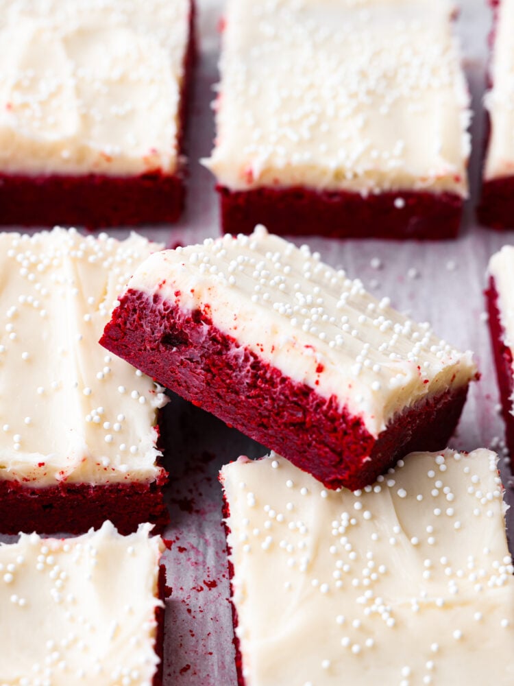 These decadent red velvet sugar cookie bars with cream cheese frosting are so divine. This is the best of both worlds, all the goodness of red velvet cake in an easy-to-make cookie bar form. Closeup of red velvet cookie bars.