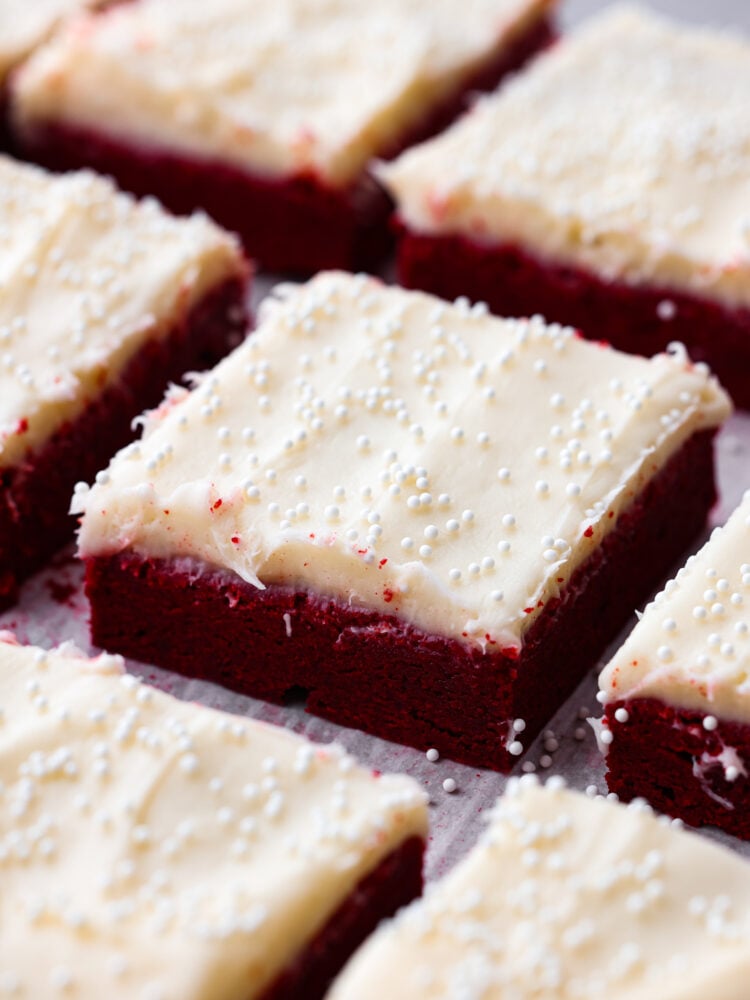 These decadent red velvet sugar cookie bars with cream cheese frosting are so divine. This is the best of both worlds, all the goodness of red velvet cake in an easy-to-make cookie bar form. Red velvet sugar cookie bars cut into squares.