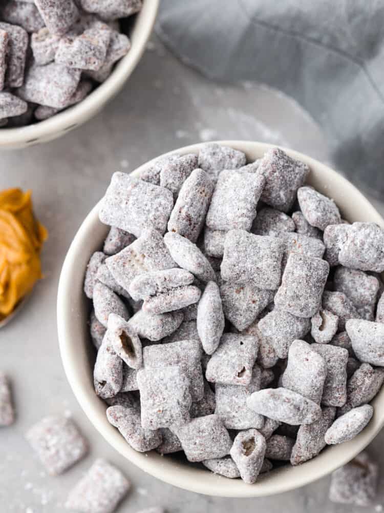 If you crave a peanut butter and chocolate snack with less calories, these Skinny Muddy Buddies are your new best friend! They taste just as good as the muddy buddies you remember, without the guilt. Muddy buddies in a white and black bowl