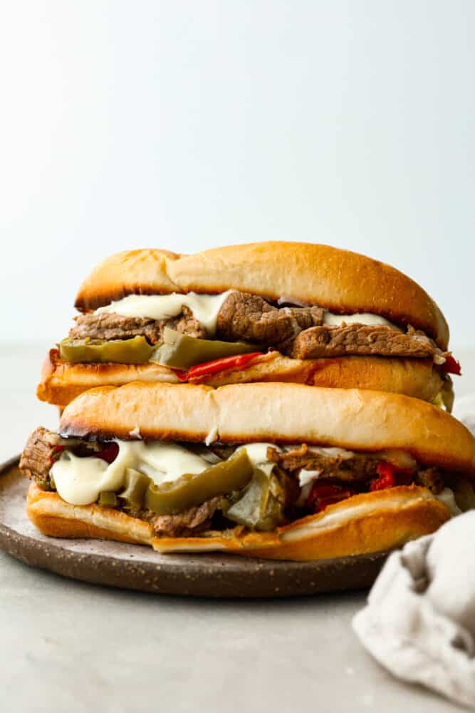 You'll never want to make a Philly cheesesteak any other way! Slow Cooker Philly Cheesesteaks are juicy and tender meat cooked in the slow cooker and perfectly topped with melty cheese on a toasted bun! Slow cooker philly cheesesteaks on a plate.