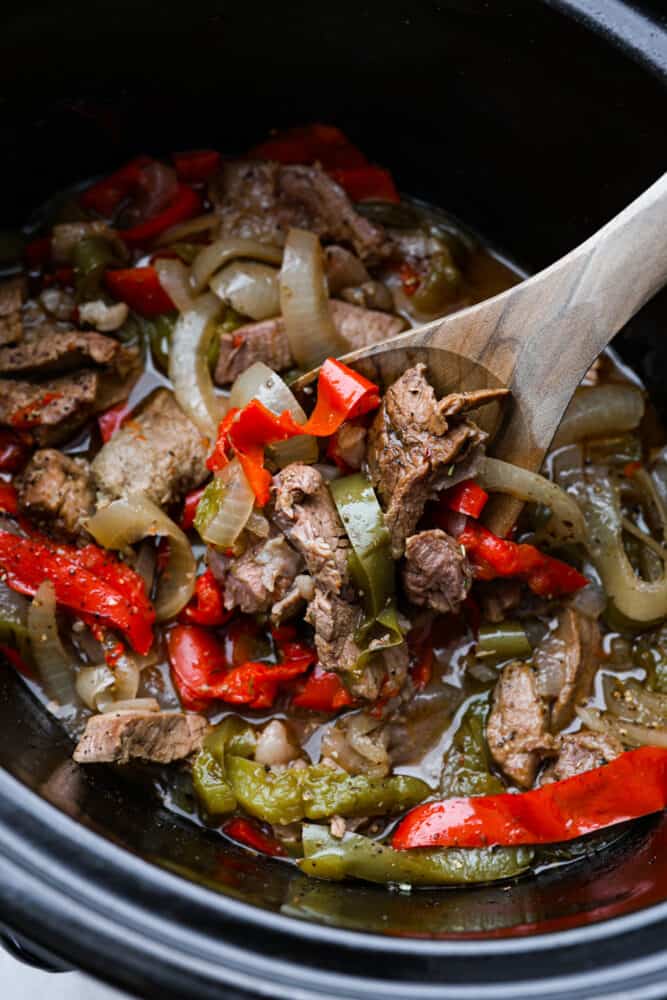 You'll never want to make a Philly cheesesteak any other way! Slow Cooker Philly Cheesesteaks are juicy and tender meat cooked in the slow cooker and perfectly topped with melty cheese on a toasted bun! A close up look at the meat in the slow cooker.