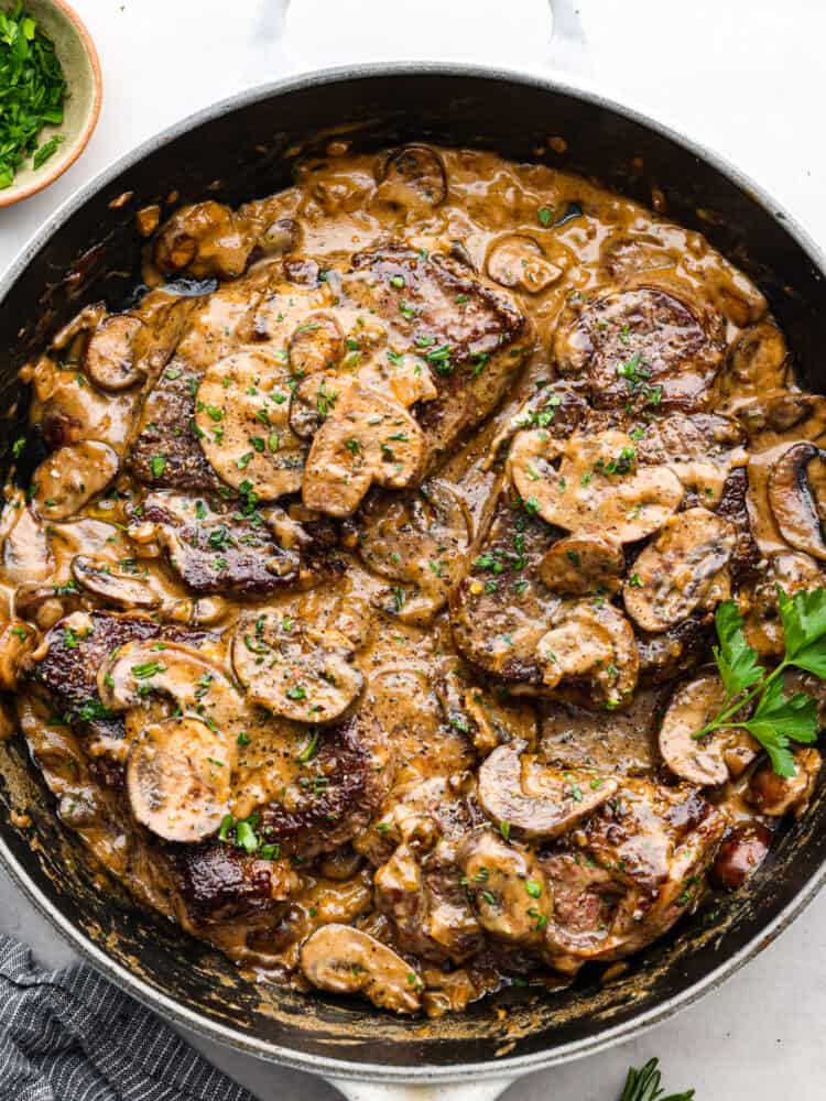 Juicy and succulent Steak Diane is the perfect dinner for any occasion. Diane refers to the delicious cream sauce made that includes mustard, Worcestershire sauce, and Cognac. The steak is flattened and seared in butter, and couldn't be more flavorful! An overhead view of steak diane on a black plate.