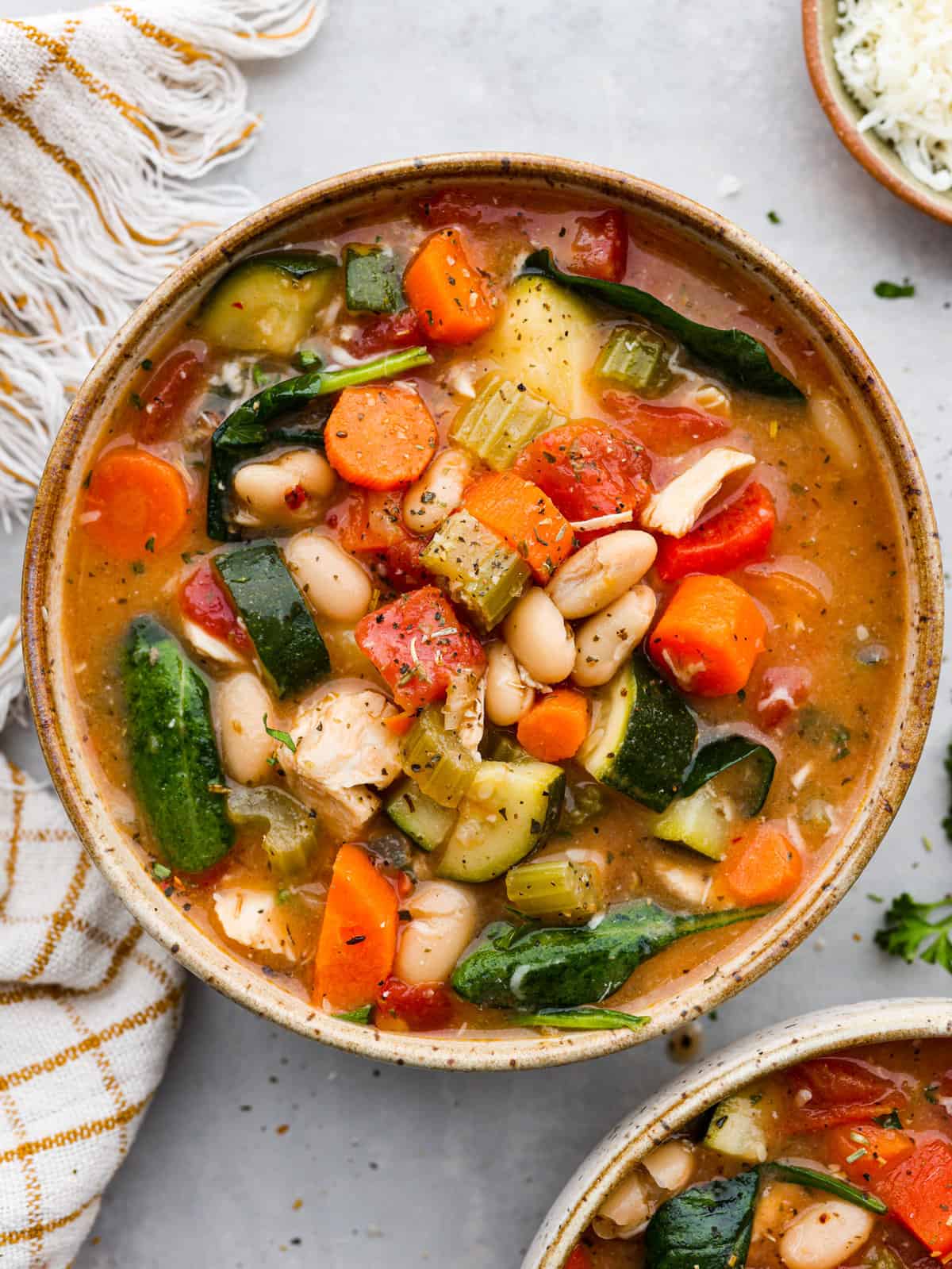Tuscan vegetable chicken stewย is so comforting and full of hearty vegetables, white beans and chicken. Super easy to makeย andย perfect for busy weeknights! Tuscan vegetable chicken soup served in a stoneware bowl.