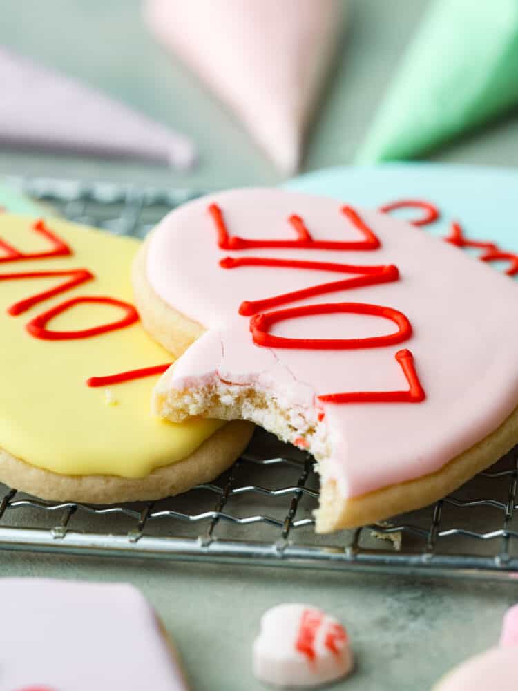 Show your sweetheart how much you care with these adorable Valentine's Day cookies! Conversation heart cookies are fun and nostalgic and are customizable with sweet and silly messages. They are delicious, easy to make, and totally unforgettable! A close up on the sugar cookie with a bite taken out of it.