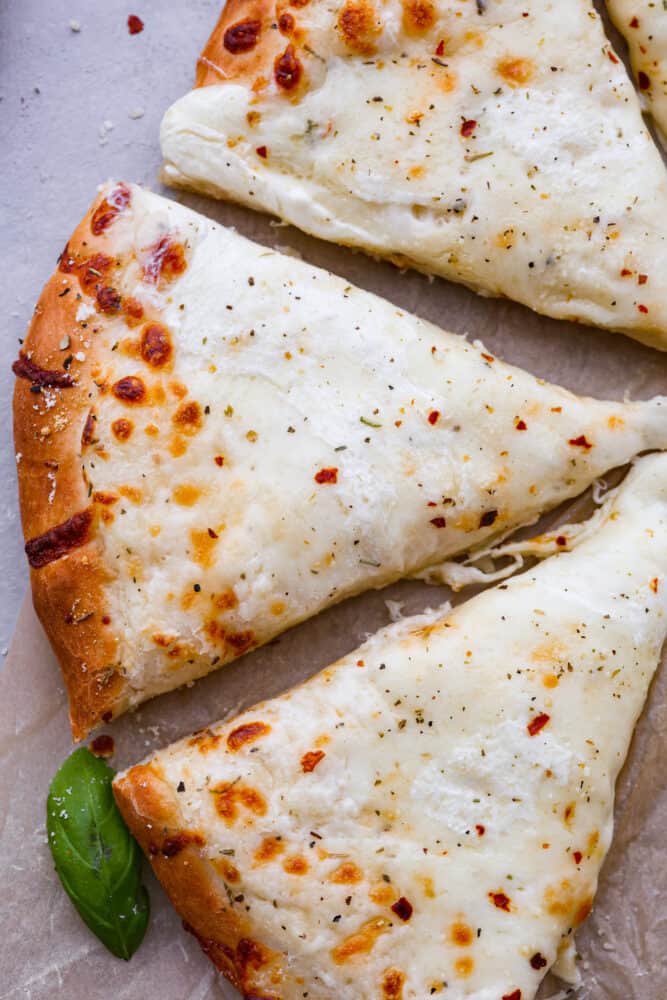 White Pizza, also called pizza bianca, is a delicious and soft and chewy pizza crust topped with a creamy Parmesan sauce and mozzarella cheese. There's every reason to fall in love with this recipe. It's quick and easy and a total hit! An up close look at a few slices.