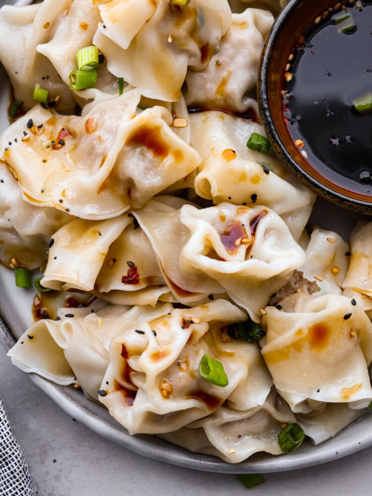 Skip the takeout and make these irresistible pork wontons at home! Theyโre soft and juicy and filled with mouthwatering seasoned pork. You wonโt be able to stop at one! Closeup of pork wontons.