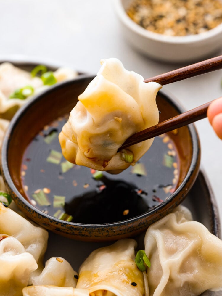 Skip the takeout and make these irresistible pork wontons at home! Theyโre soft and juicy and filled with mouthwatering seasoned pork. You wonโt be able to stop at one! A pork wonton being dipped in sauce with chopsticks.