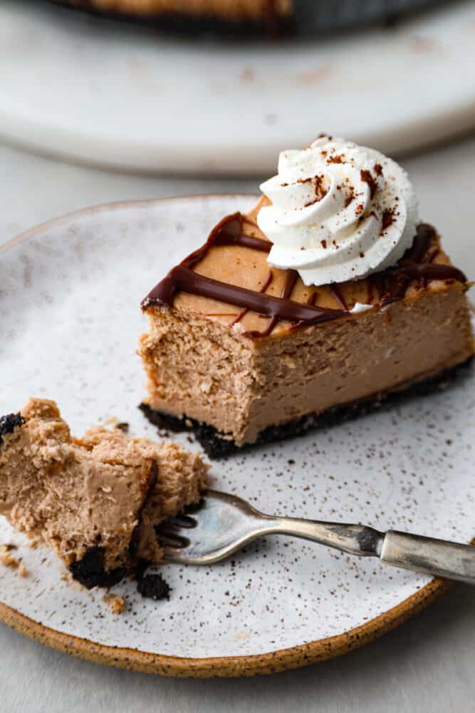 Indulge in creamy bliss with every bite of this Baileys Cheesecake - a rich and decadent dessert that's perfect for satisfying your sweet cravings! It has a smooth, chocolatey filling flavored with Bailey’s Irish Cream liqueur on top of a rich Oreo crust. A slice of cheesecake with a bite taken out of it.