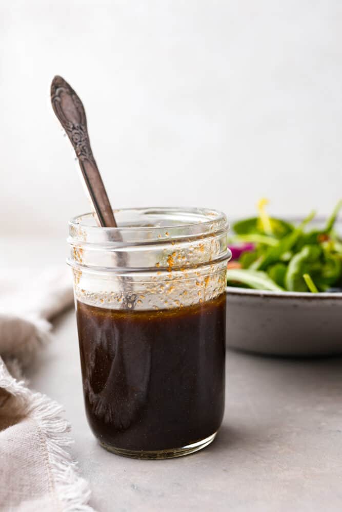 Balsamic Vinaigrette is a staple in the kitchen that every cook should have the perfect recipe for. THIS is that perfect recipe! It's tangy and refreshing, and will spruce up your salads and better than every other recipe I've ever tried. Balsamic vinaigrette in a mason jar with a spoon in it.