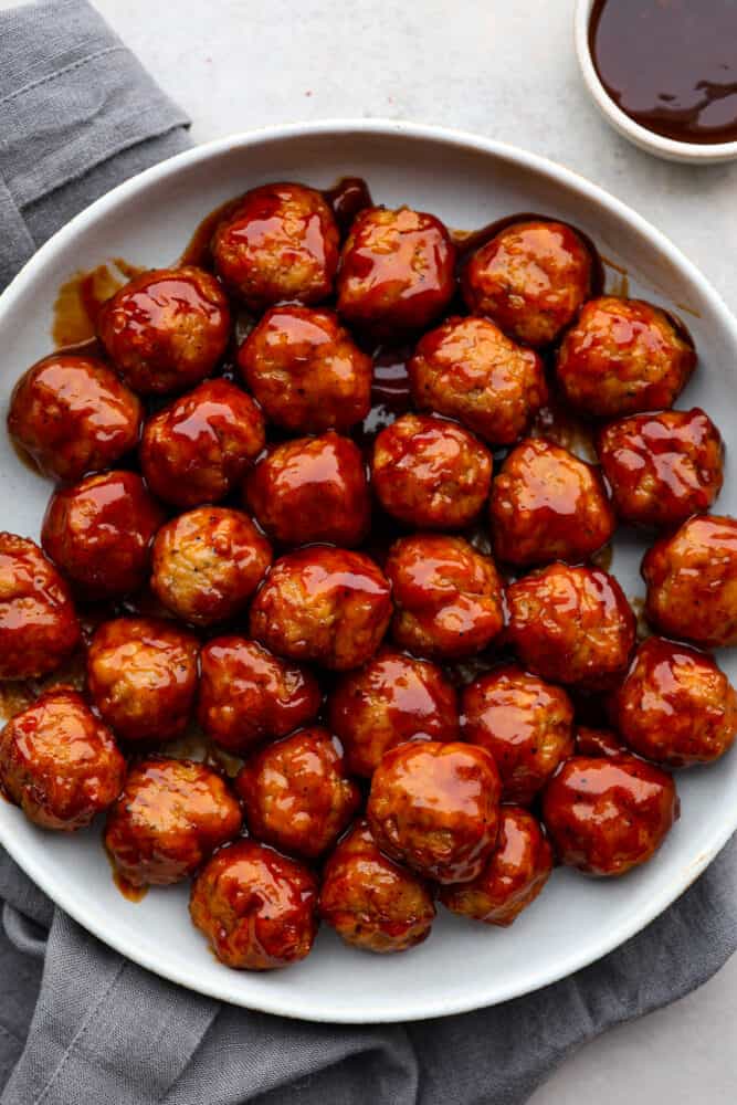 BBQ Meatballs are cooked in a slow cooker and smothered in a delicious barbecue sauce. They are the easiest meatball recipe you'll ever try, and they are perfect for parties and simple appetizers. BBQ meatballs on a plate.