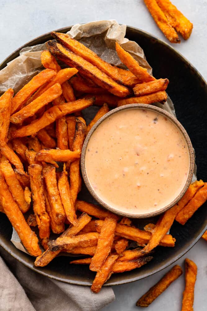 Boom Boom Sauce is a sweet and spicy mayonnaise-based sauce that is perfect for dipping! It takes 5 minutes to whip up and is so full of flavor, making it perfect for fries, onion rings, and so much more. A bowl of sauce with french fries around it.