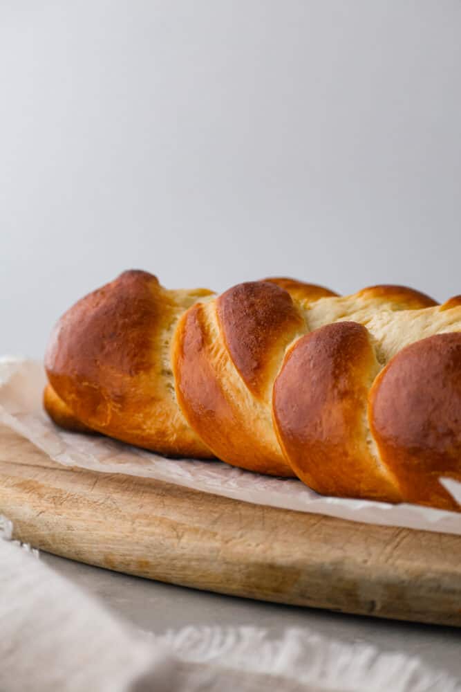 If you want to start making more bread at home, this brioche bread is the perfect place to start! Not only is it beautiful, fluffy, and super delicious, it's also really easy to make. This bread is perfect for sandwiches, French toast, or just eating plain! A brioche loaf sitting on parchment.