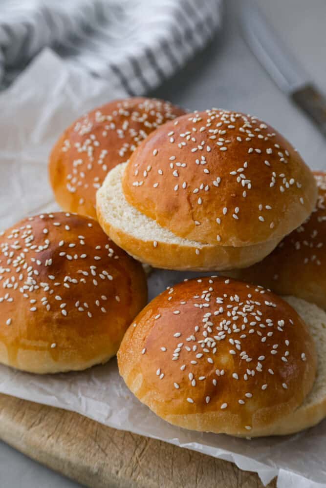 A good hamburger bun can make all the difference! This Brioche Bun is hands down the BEST bun for hamburgers, sloppy joes, and so much more. It's fluffy, soft, and oh so good. Brioche buns stacked on top of a cutting board.
