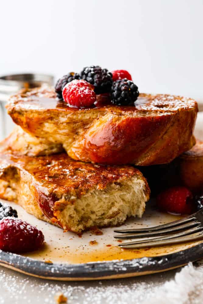 Move over regular French toast, there's a new brunch boss in town and it's made with brioche bread! With its buttery richness and pillowy texture, it's like biting into a cloud of happiness. Trust me, once you've had brioche French toast, there's no going back to the basic stuff. Itโs breakfast, elevated! Two slices of brioche French toast, one has a bite taken out of it.