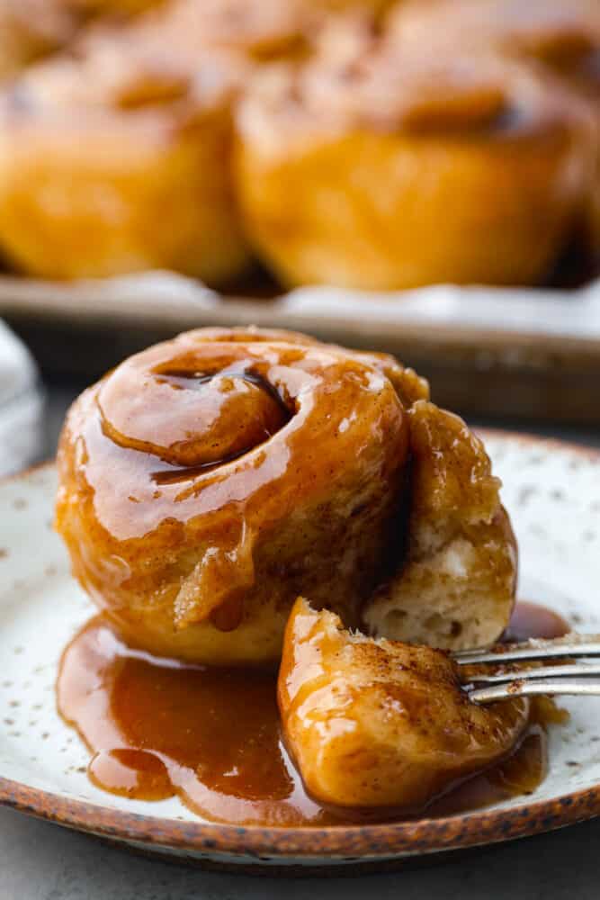 Caramel Rolls are as heavenly as they sound! Delicious and delicate cinnamon rolls are covered in caramel sauce that melts into every nook with absolutely divine flavor in every bite. I am not kidding when I say this is a next-level dessert experience! A caramel roll on a plate with a fork.