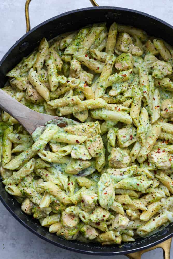 Chicken Pesto Pasta is made creamy with Parmesan, mozzarella, and heavy cream. Fresh basil pesto coats this pasta and chicken for the perfect pop of flavor in every bite. This is a quick and easy recipe that everyone will love! A close up of the pesto pasta in the pan.