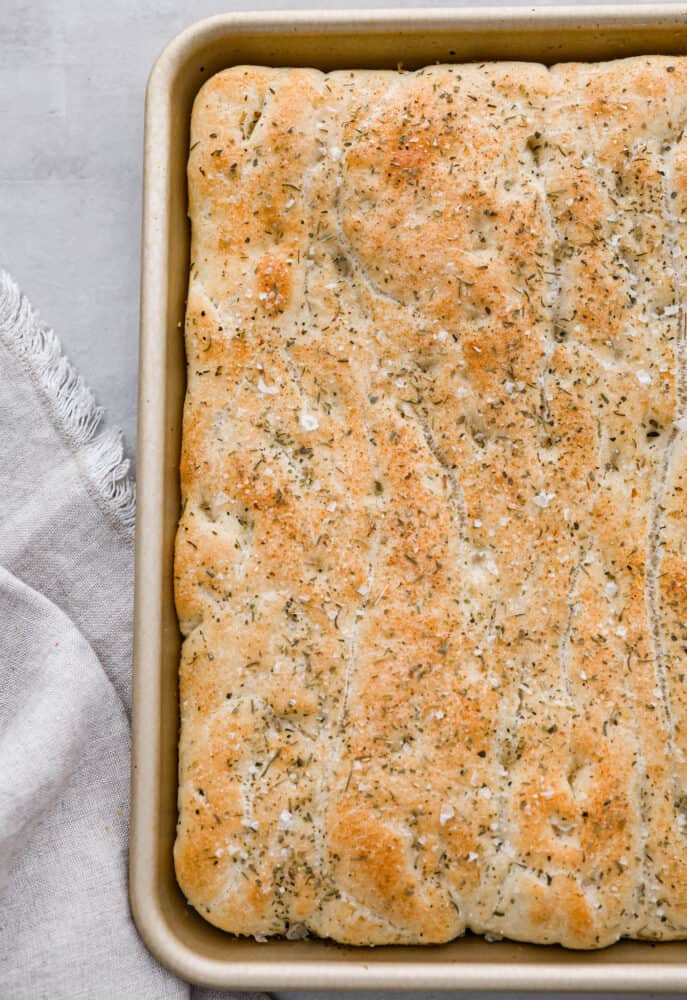 This Focaccia Bread recipe is easier than you think! Made with just a few ingredients and brushed with olive oil and Italian herbs, it's the perfect complement to any meal! A whole pan of focaccia bread.