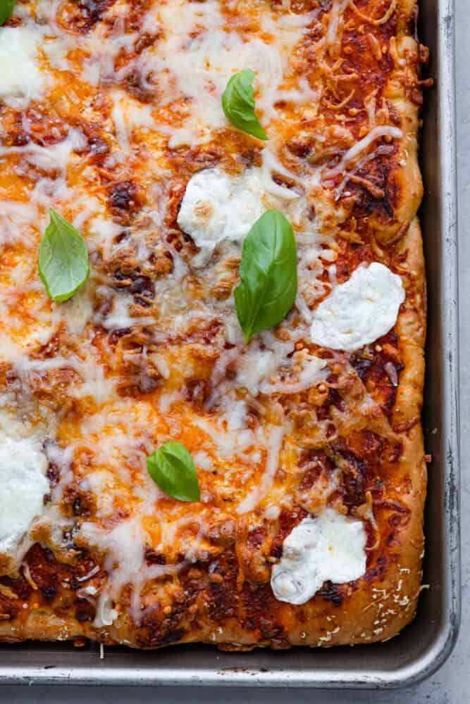 As if focaccia bread wasnโt good enough, now you can level it up with your favorite pizza toppings! Focaccia pizza is cheesy and flavorful, all on top of the most soft and dreamy crust! Top-down view of focaccia pizza in the pan.
