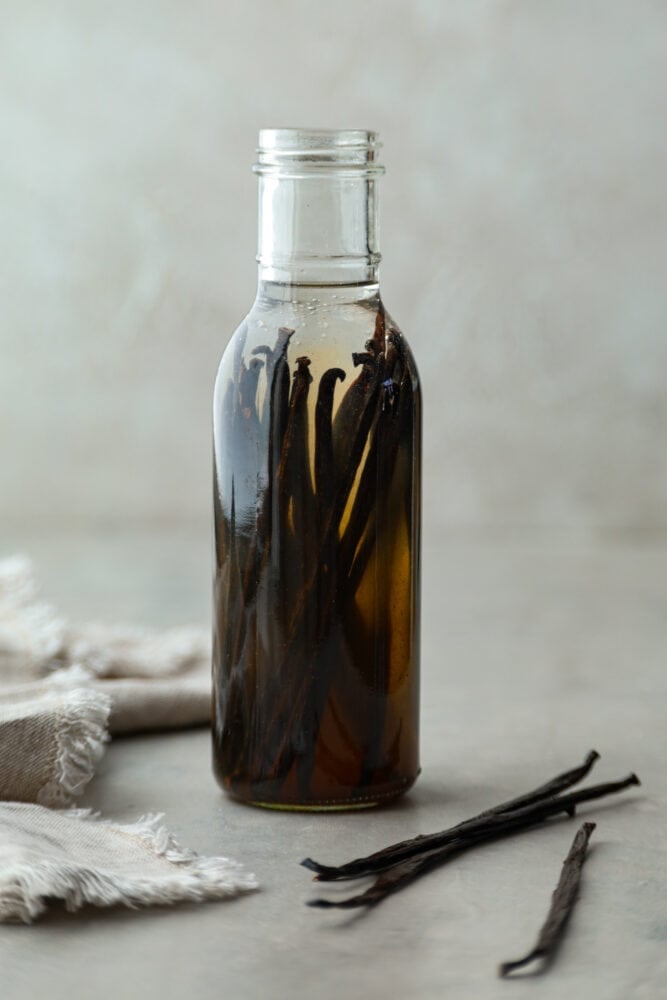 Making your own homemade blend of vanilla extract is quick and easy. Trust me, it will take all of your recipes to the next level! Plus, it only takes 2 simple ingredients to whip up! Hero image of vanilla beans in a glass jar being extracted by a clear alcohol.