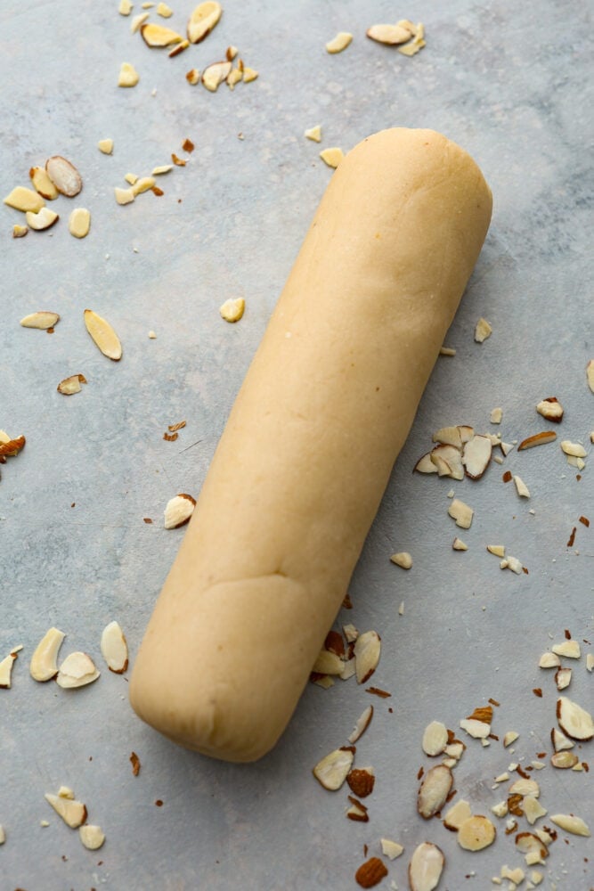 This Easy Homemade Marzipan will take your baking to the next level! It's a quick and simple recipe that will bring delicious almond flavor to your cakes and cookies. It's also easily colored and shaped into fun decorations! A picture of a log of marzipan.