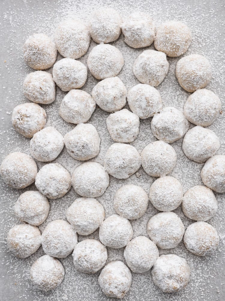 Mexican wedding cookies are buttery, nutty, and coated in powdered sugar that makes them oh-so-good. They are usually a celebratory dessert, but they are so yummy you will want them all the time! Mexican wedding cookies on a counter top covered in powdered sugar.