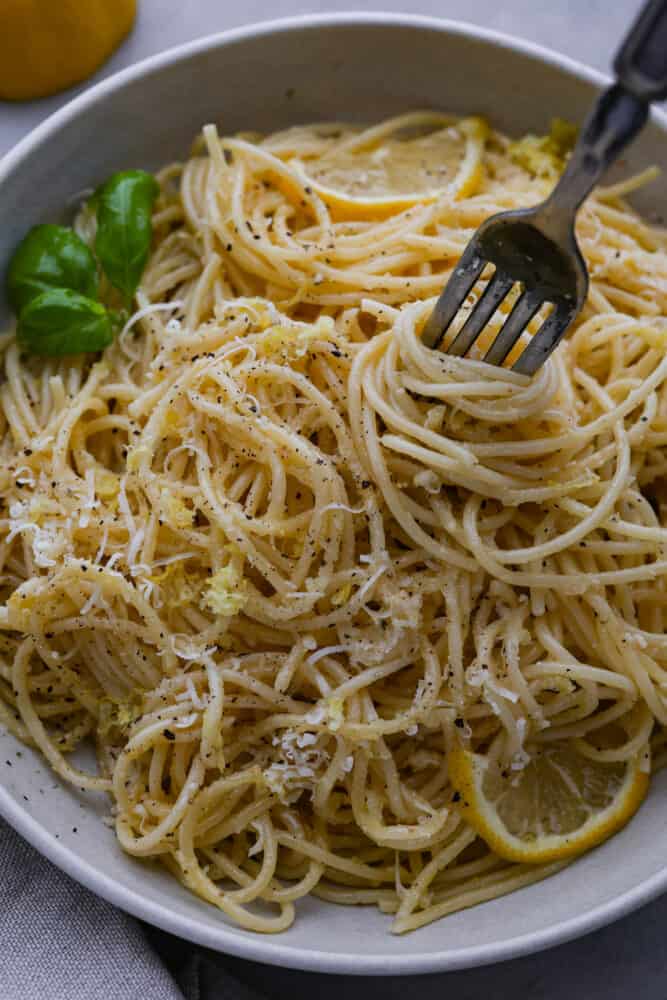 Pasta al limone is a really simple and classic Italian dish of long noodles and a parmesan and lemon topping. It is covered in melted butter and tangy lemon, and is the perfect thing to cook for dinner when you don't know what to make! A fork scooping up pasta al limone.