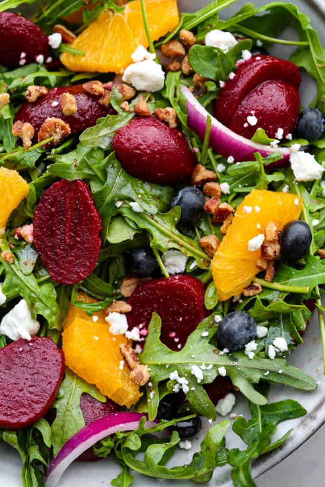 This roasted beet salad will have you singing the praises of this root veggie and begging for seconds! It's tossed with fruit, nuts, and crumbled cheese all coated in a delicious homemade balsamic vinaigrette. A light lunch that's both healthy and delicious! Closeup of roasted beet salad.