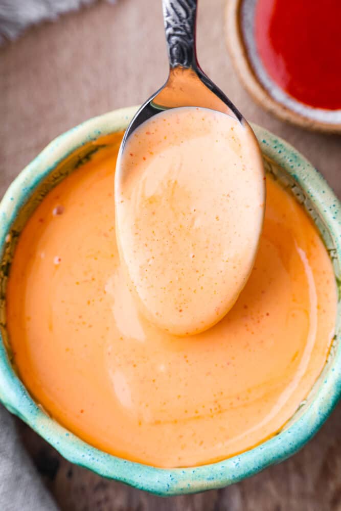 Sriracha mayo is the condiment youโre going to want to put on everything! Itโs creamy and savory, with spice that packs a punch! Closeup of sriracha mayo in a green bowl.